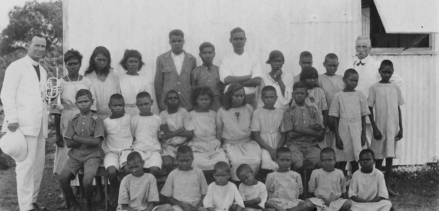 Photo showing some young members of the stolen generation standing between two older white men